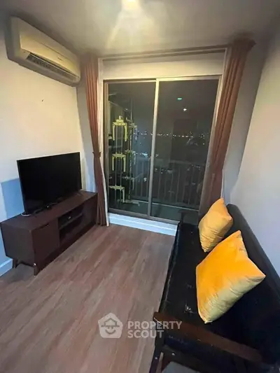 Cozy living room with balcony view, featuring modern TV setup and comfortable seating.
