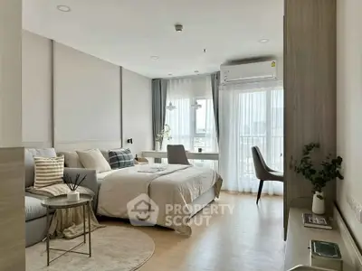 Modern studio apartment with cozy bed, stylish decor, and natural light from large windows.