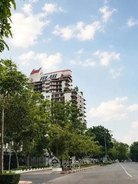 Stunning high-rise building with lush greenery and clear blue sky