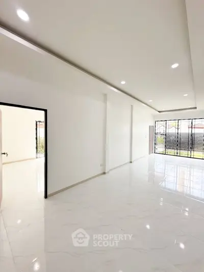 Spacious modern living room with large windows and sleek white flooring.