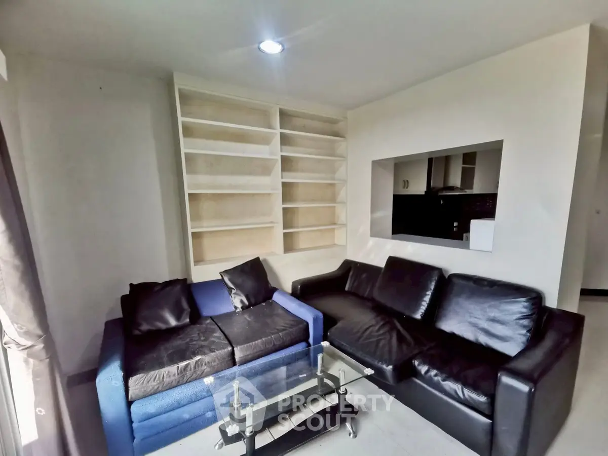 Modern living room with sleek black leather sofas and built-in shelving