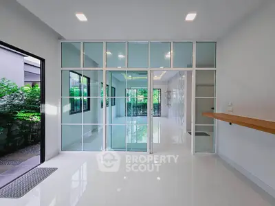 Spacious modern interior with glass partitions and garden view, ideal for open living spaces.