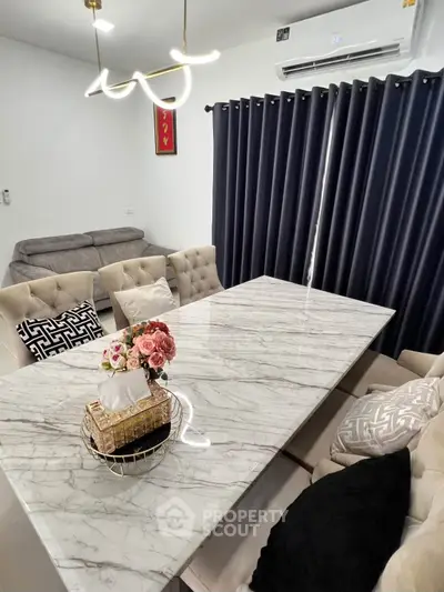 Elegant dining area with marble table, plush chairs, and modern lighting in a cozy living space.