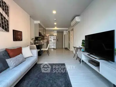 Modern living room with sleek furniture and open kitchen layout in a stylish apartment.