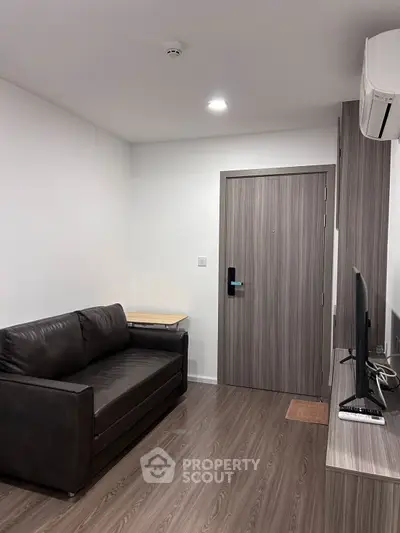 Modern living room with sleek sofa and wall-mounted TV in minimalist apartment.