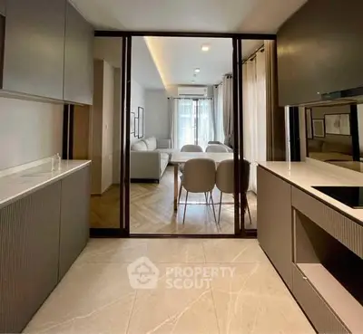 Modern kitchen with sleek cabinetry leading to a stylish living room with elegant dining area.