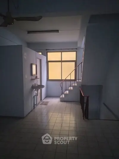 Spacious interior with staircase and window, ideal for creative renovation.