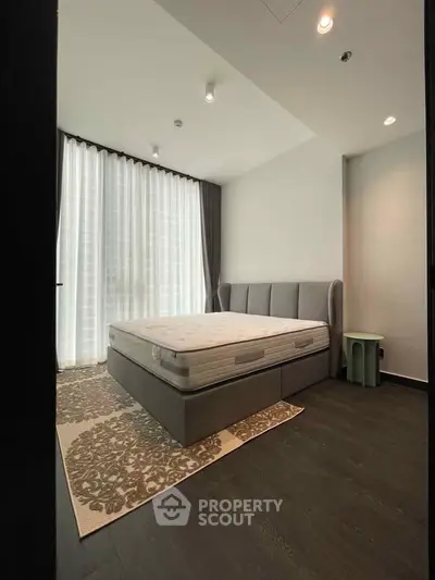 Modern bedroom with large window and stylish decor in a contemporary apartment.