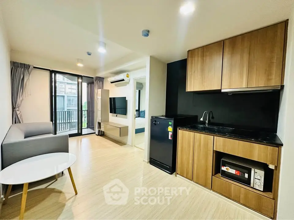 Modern open-layout living room with kitchenette, featuring sleek wooden cabinets and a cozy seating area.
