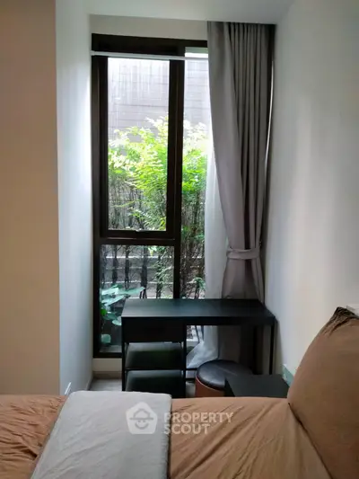 Cozy bedroom with large window and garden view, featuring a small desk and comfortable bedding.