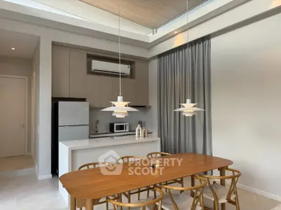Modern kitchen with open layout and stylish dining area featuring pendant lights and wooden furniture.