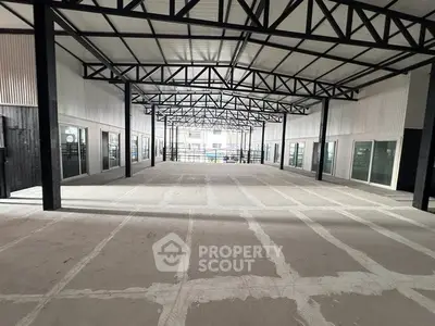 Spacious industrial warehouse with high ceilings and steel beams, ideal for storage or manufacturing.