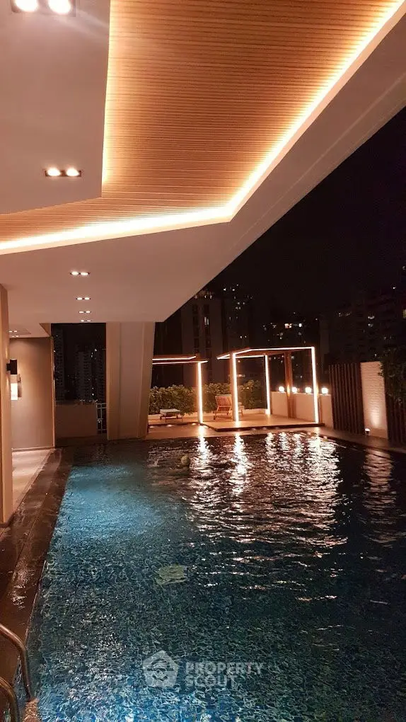 Luxurious rooftop pool with ambient lighting and city skyline view at night.