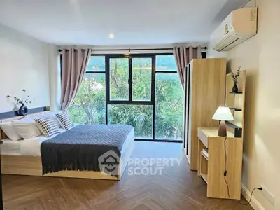 Modern bedroom with large window and stylish decor, featuring a cozy bed and wooden furniture.