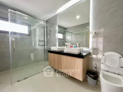 Modern bathroom with dual sinks and glass shower enclosure in a stylish home.