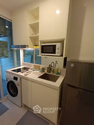 Modern compact kitchen with washing machine and microwave in sleek apartment