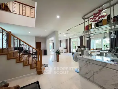 Spacious open-plan living area with modern kitchen and elegant staircase in a luxurious home.