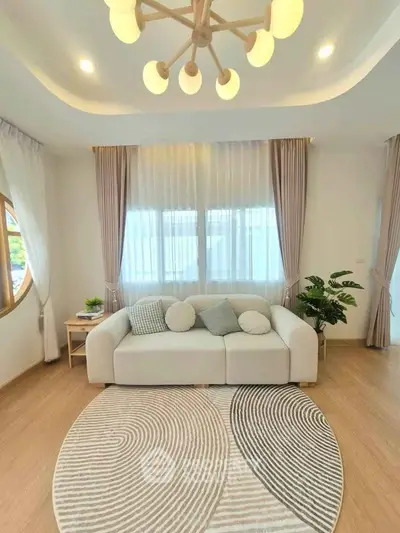 Elegant living room with modern decor, featuring a cozy sofa, stylish lighting, and a chic round rug.