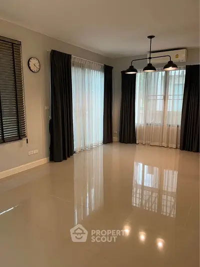 Spacious empty living room with large windows and elegant curtains