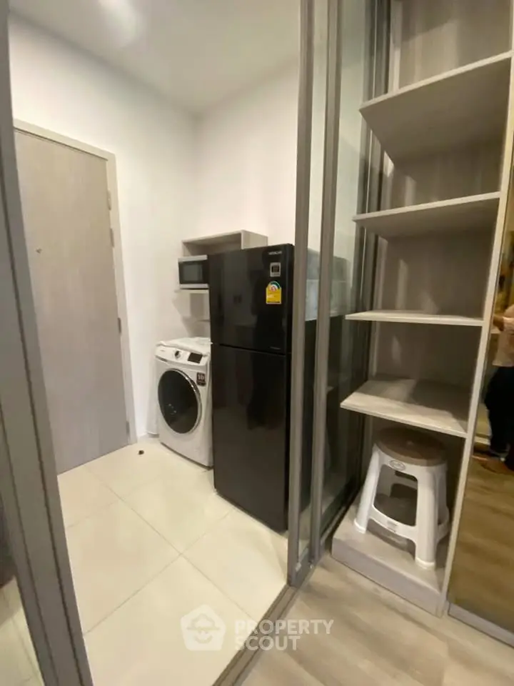 Compact laundry and storage area with modern appliances and shelving in a sleek apartment.