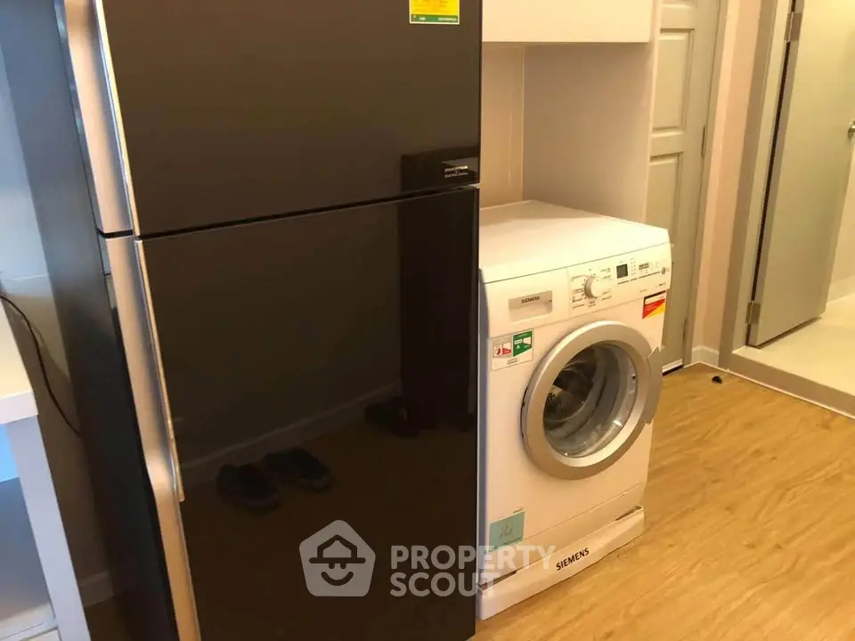 Modern apartment with sleek fridge and washing machine in utility area.