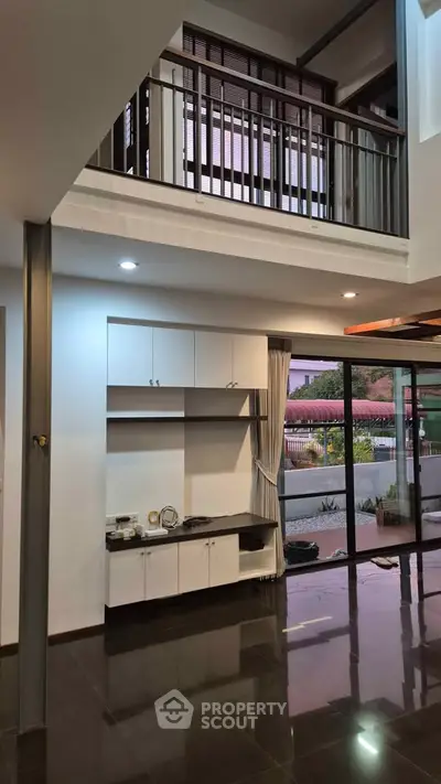 Spacious modern living room with high ceiling and large windows offering natural light and garden view.
