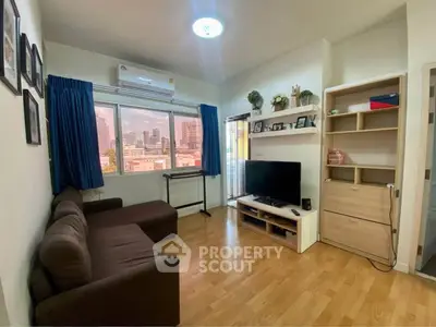 Cozy living room with city view, featuring a brown sofa, TV, and wooden flooring.