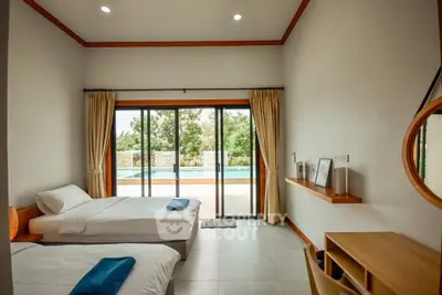 Spacious bedroom with pool view and modern decor, featuring twin beds and large sliding glass doors.