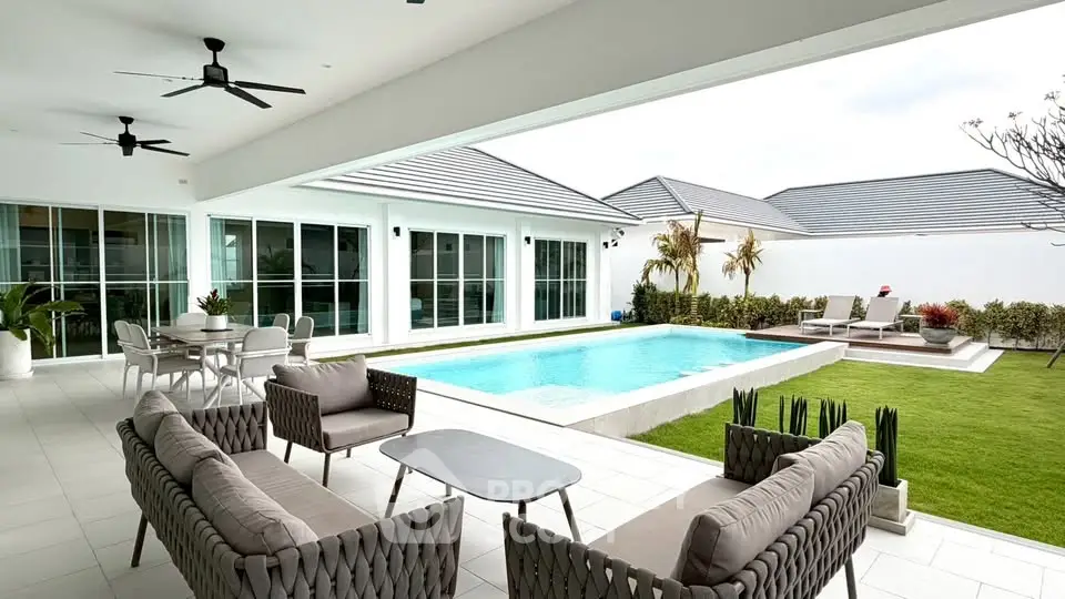 Luxurious modern patio with pool and stylish outdoor seating in a serene residential setting.
