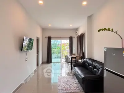 Modern living room with sleek black sofa, wall-mounted TV, and balcony view.