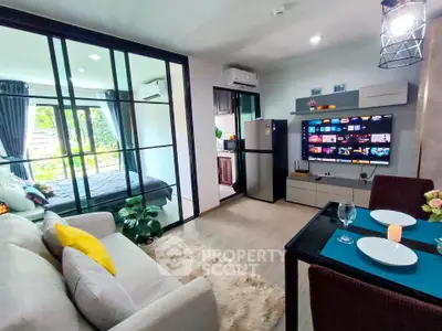 Modern open-plan living room with cozy decor and natural light, featuring a view into the bedroom.