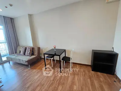 Modern living room with wooden flooring, cozy sofa, and dining table in a bright apartment.