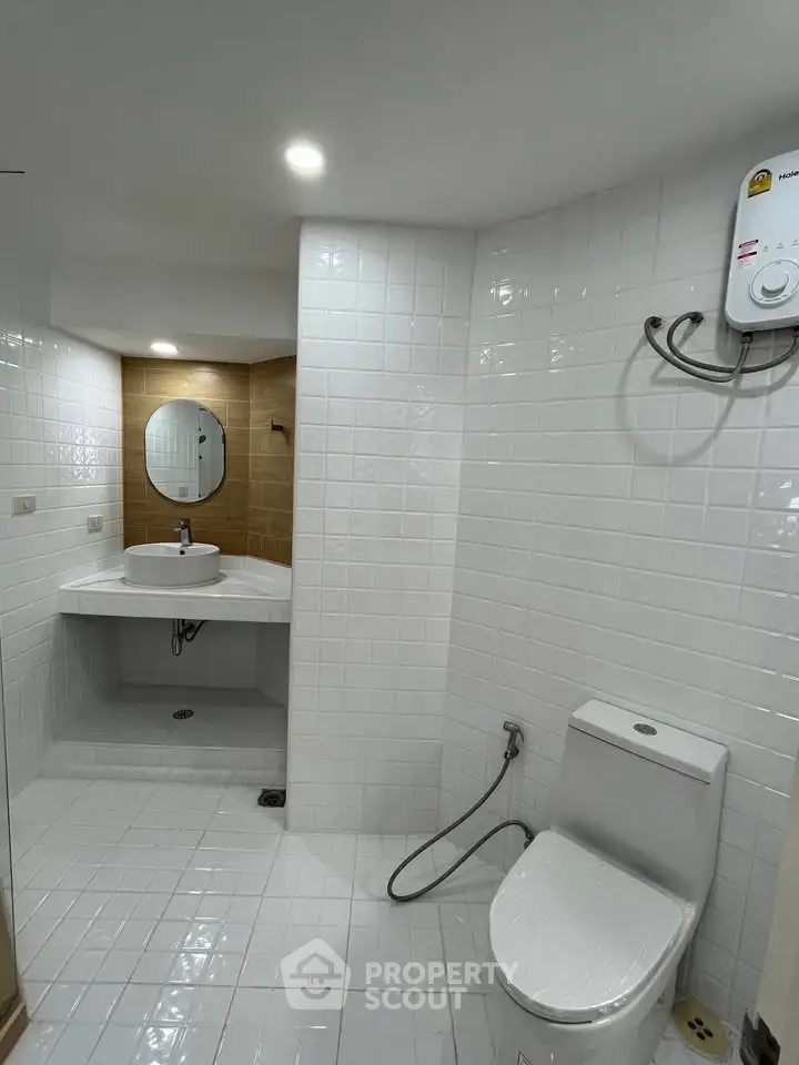 Modern bathroom with white tiles, round mirror, and sleek fixtures in a contemporary home.