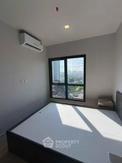 Modern bedroom with large window offering city view, featuring minimalist design and air conditioning.