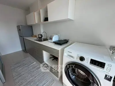 Modern kitchen with sleek appliances and ample storage space, featuring a washing machine and refrigerator.