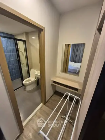 Compact bathroom with modern fixtures and adjacent vanity area in a cozy apartment.