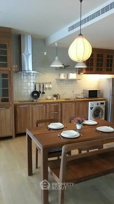 Charming kitchen with wooden cabinets and dining table, featuring modern appliances and cozy lighting.