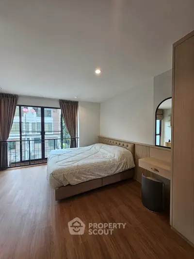 Spacious bedroom with large windows and modern furnishings in a stylish apartment.