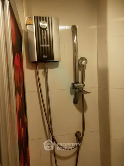 Compact bathroom shower area with modern water heater and sleek fixtures.
