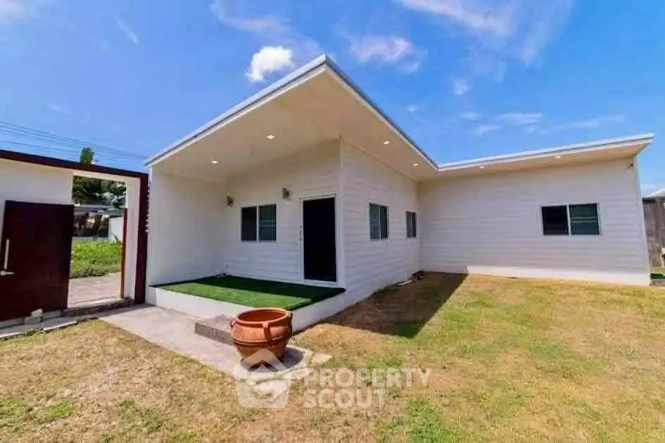 Modern single-story home with minimalist design and spacious yard under clear blue sky.