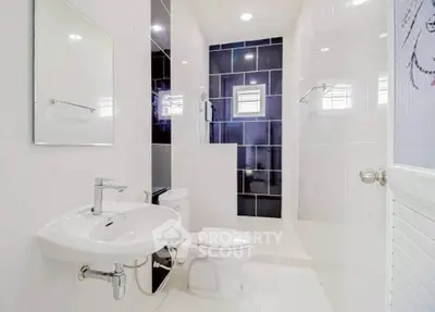 Modern white bathroom with sleek fixtures and spacious shower area.