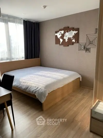Cozy bedroom with wooden flooring and stylish wall art, featuring a comfortable bed and natural light.