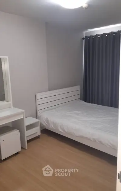Cozy minimalist bedroom with white furniture and wooden flooring, perfect for a serene living experience.