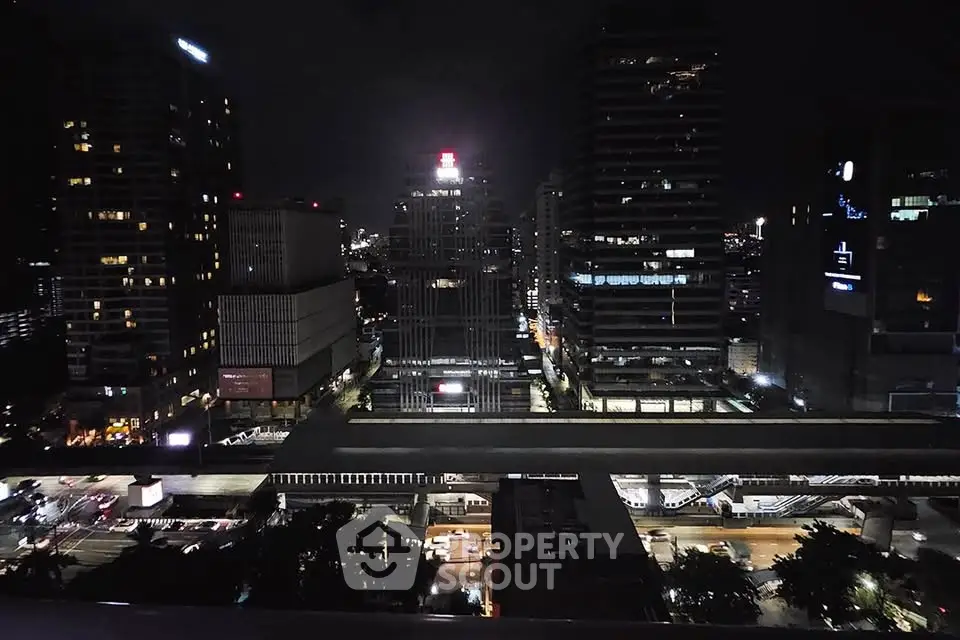 Stunning cityscape view from a high-rise building at night, showcasing vibrant urban lights and modern architecture.