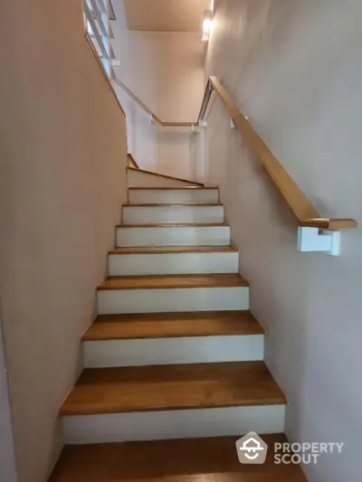 Modern wooden staircase with sleek handrail in contemporary home