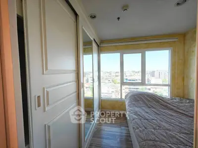 Cozy bedroom with large windows offering stunning city views and ample natural light.