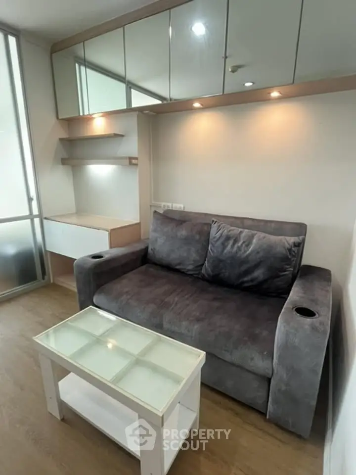Cozy living room with plush gray sofa and glass coffee table, perfect for relaxation.
