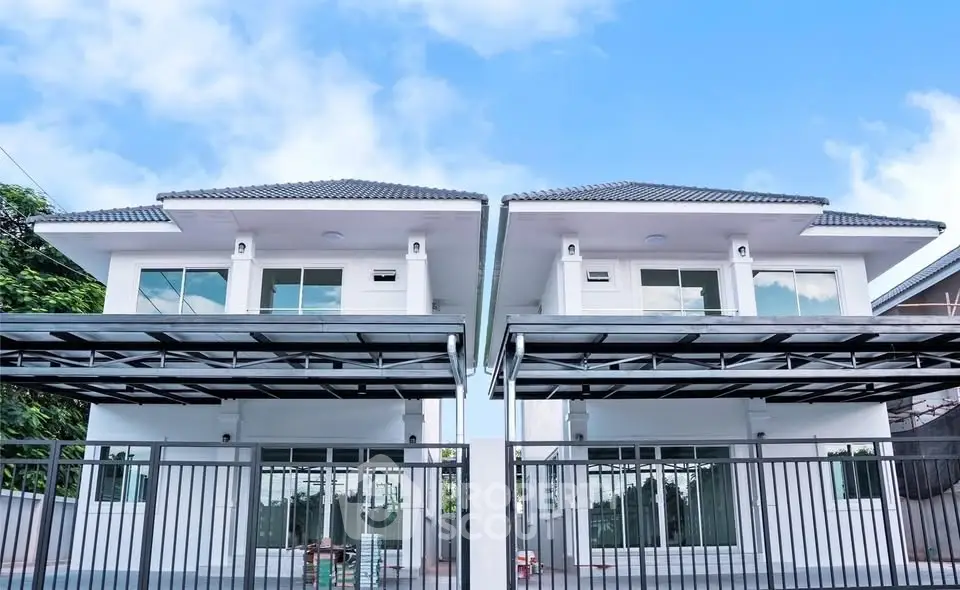 Modern twin houses with sleek design and spacious carports under a clear blue sky.