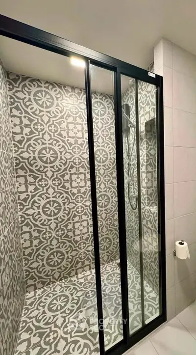Stylish bathroom with patterned tiles and modern glass shower enclosure.