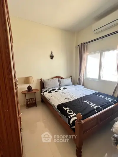 Cozy bedroom with wooden bed frame, bedside table, and natural light from window.